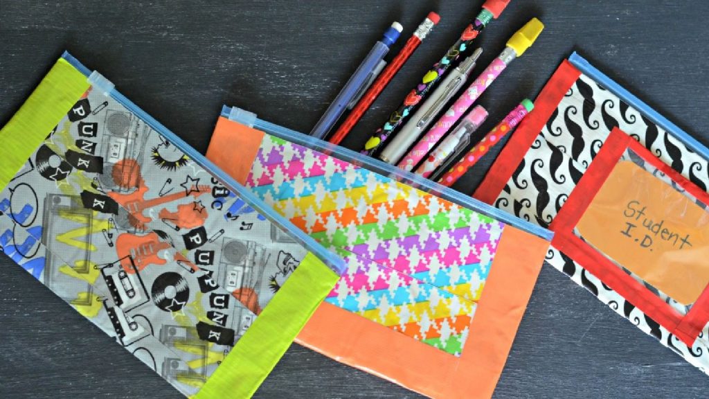 Colorful, patterned pencil cases on a table, with various pens and pencils sticking out of one case.