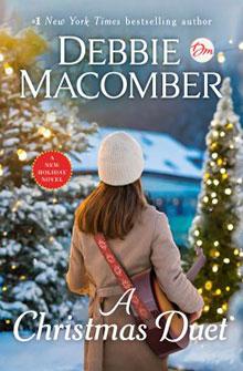 Person with a guitar looking at snowy, lit-up trees; "Debbie Macomber, A Christmas Duet" text on the book cover.