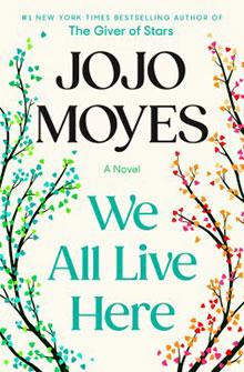 Book cover of "We All Live Here" by Jojo Moyes, featuring colorful, leafy branches on a cream background.