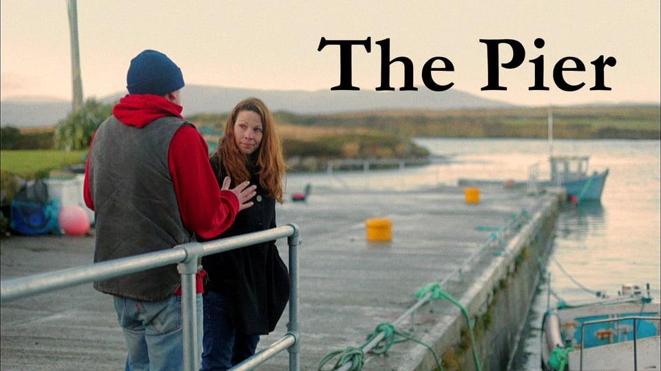 Two people talking on a pier with a boat docked nearby, under the title "The Pier.