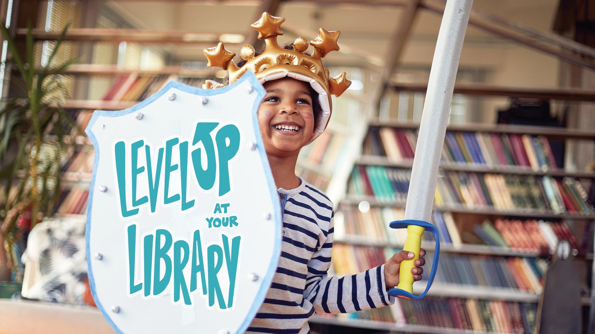 Smiling child in a crown and holding a sword and shield that reads "Level Up at Your Library" in a library.