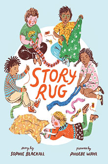 Five children sit in a circle, weaving colorful fabric strips around the words "Story Rug.