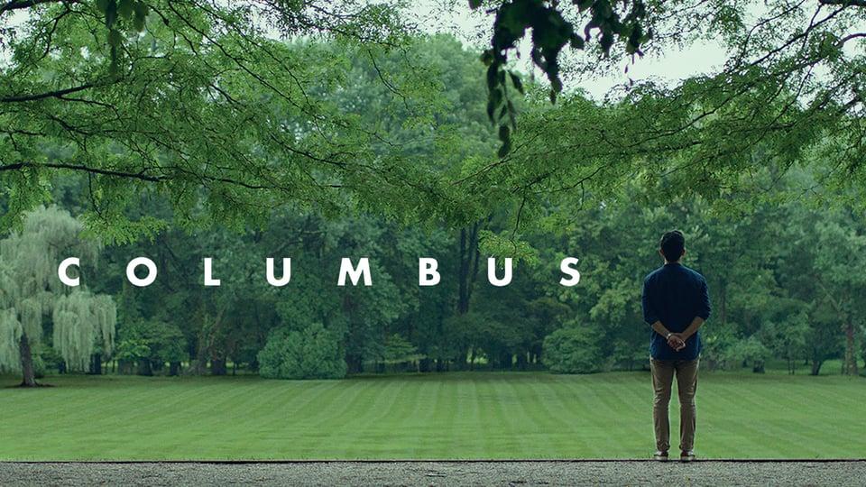 A person stands in a green park with “COLUMBUS” written across the image in large white letters.
