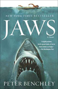 Book cover for "Jaws" by Peter Benchley, depicting a swimmer on the surface and a large shark emerging from below.