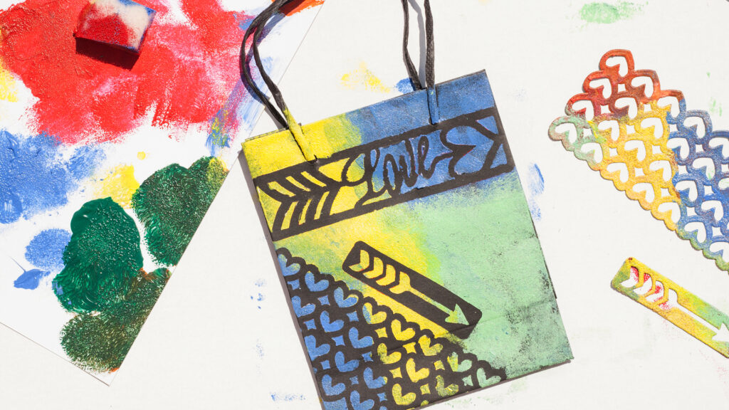 Colorful handmade card with "LOVE" text, black patterns, and paint splotches on white background.