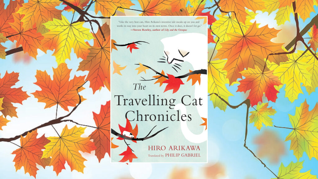 Book cover of "The Travelling Cat Chronicles" with a cat, autumn leaves, and a blue sky background.