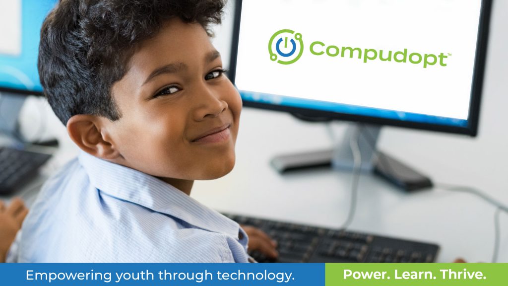 A smiling child sits at a computer with the Compudopt logo on the screen. Text: "Empowering youth through technology.