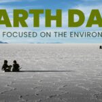 Two people sit on a vast salt flat under a blue sky with text: Earth Day, films focused on the environment.