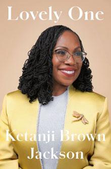 A woman with glasses and braided hair smiles, wearing a yellow blazer. Text reads: "Lovely One - Ketanji Brown Jackson.