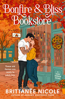 A couple kisses outside a cozy bookstore with fall leaves and warm orange tones surrounding them.