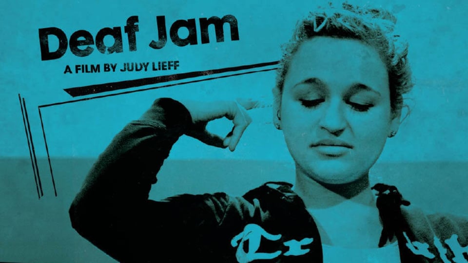 A woman in a jacket signs "I love you" on a blue poster with the text: "Deaf Jam: A film by Judy Lieff.