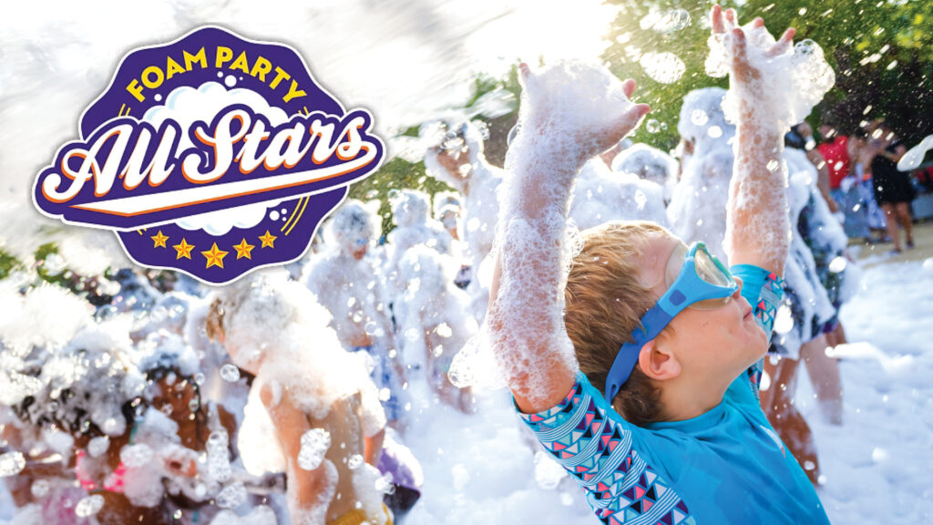 Children play in a foam-filled outdoor party, wearing swimsuits and goggles. "Foam Party All Stars" logo is visible.