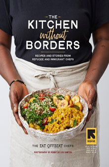 Person holding a dish of colorful food with the book title "The Kitchen Without Borders" in the background.