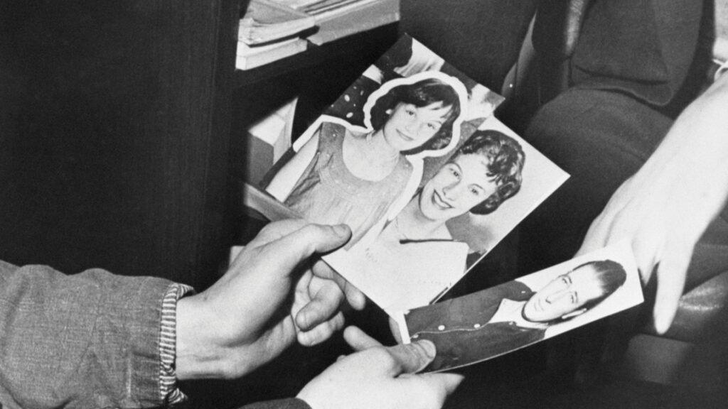 Three hands hold black-and-white photos of two women and one man, shown close up.