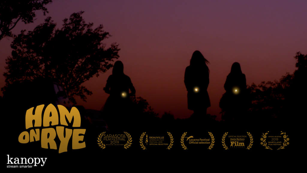 Three silhouetted figures walk at sunset with lights in hand; "Ham on Rye" title and festival awards visible.