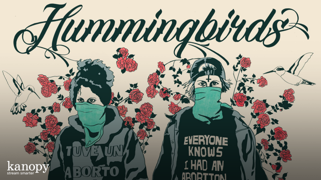 Two masked figures in front of roses, with "Hummingbirds" and hummingbirds above, wearing pro-abortion shirts.