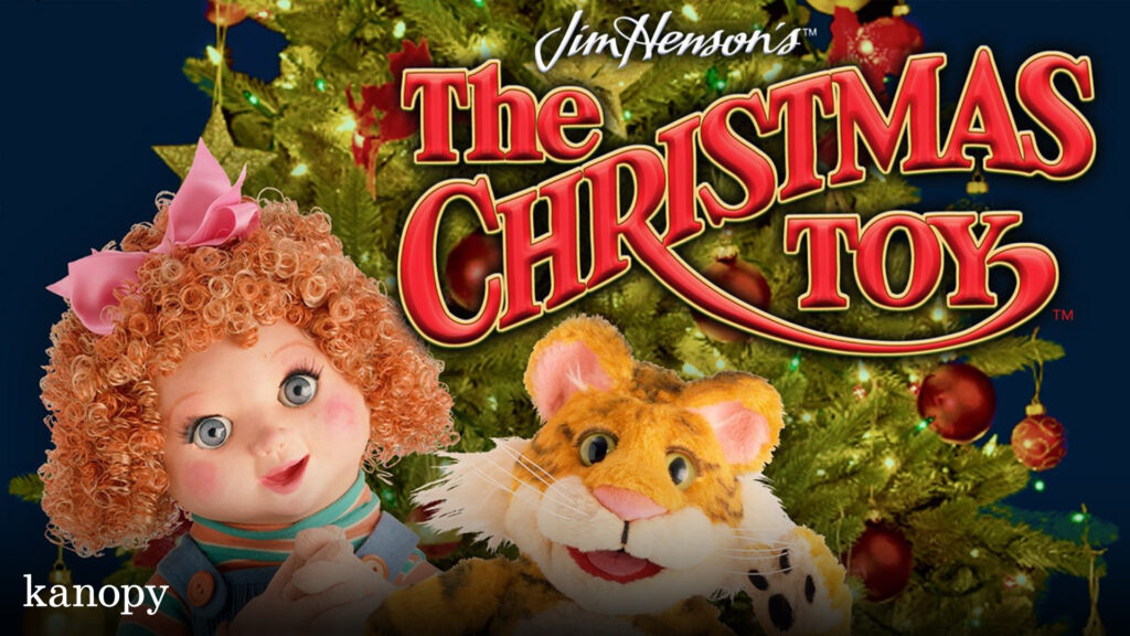 A curly-haired doll and a plush tiger in front of a Christmas tree with "The Christmas Toy" title.