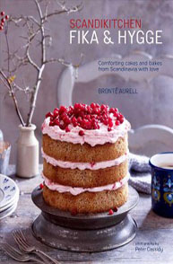 Cover of "Scandikitchen: Fika & Hygge" book showing a layered cake with pink frosting and red berries on top.