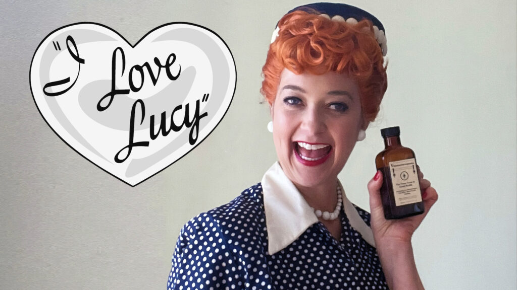 Smiling woman in vintage polka dot dress holds bottle; "I Love Lucy" text in heart shape beside her.
