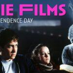 Three people, including one in a rabbit costume, sit in a dark theater with "Indie Films for Independence Day" text.