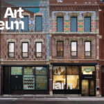 Street view of the Intuit Art Museum, showing its brick facade with colorful patterns and large front windows.