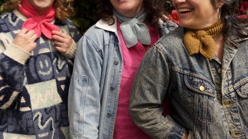 Three people wearing colorful scarves and denim jackets, standing close together, partially shown from shoulders up.