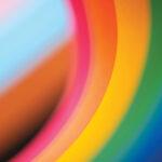 Close-up of colorful curved stripes, including pink, yellow, orange, green, and blue, creating an abstract pattern.