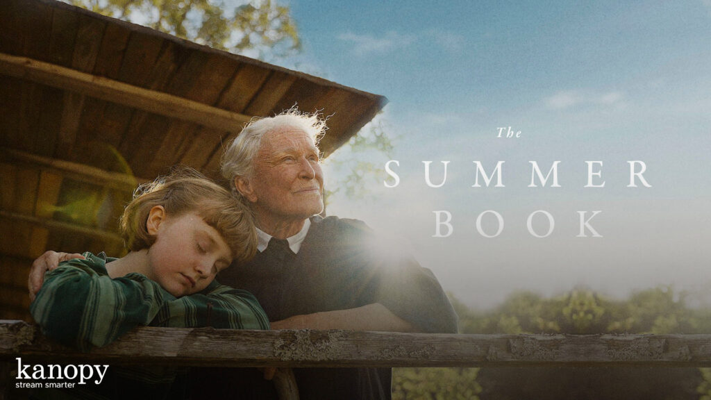 An elderly person and a child lean on a wooden fence, with “The Summer Book” text in sunlight.