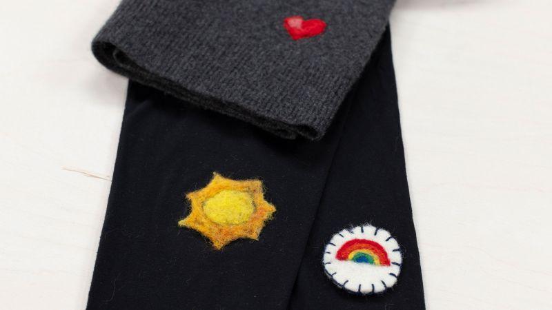 Black and gray fabric with felt patches: a heart, sun, and rainbow.