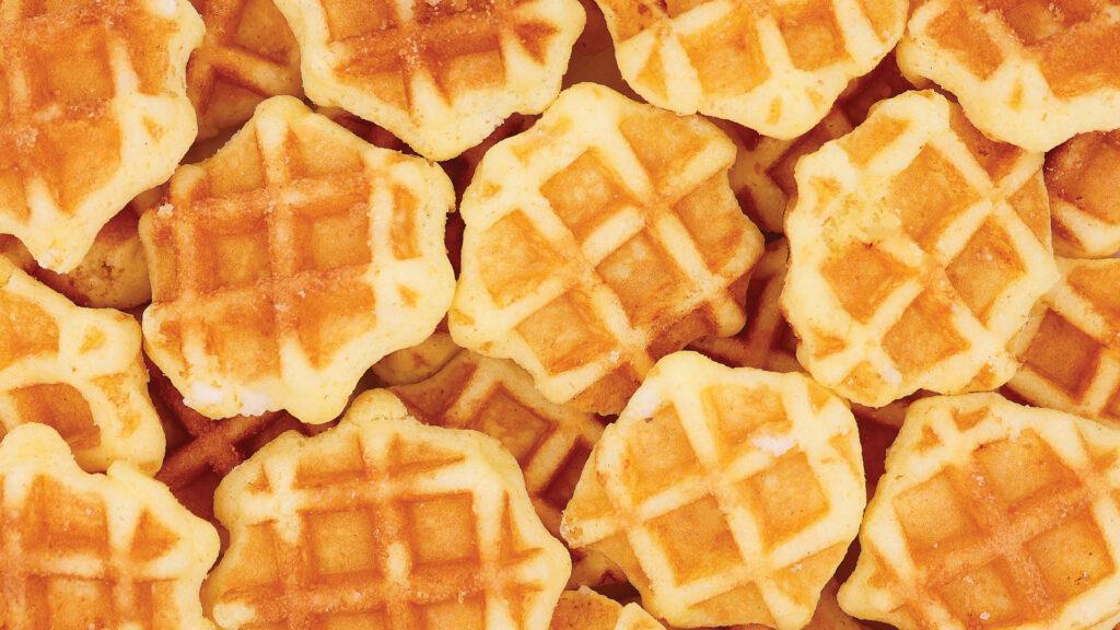 Golden waffles stacked closely together, showing their grid pattern and crispy texture.