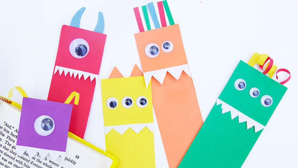 Colorful monster-themed bookmarks with googly eyes and paper teeth on an open book.