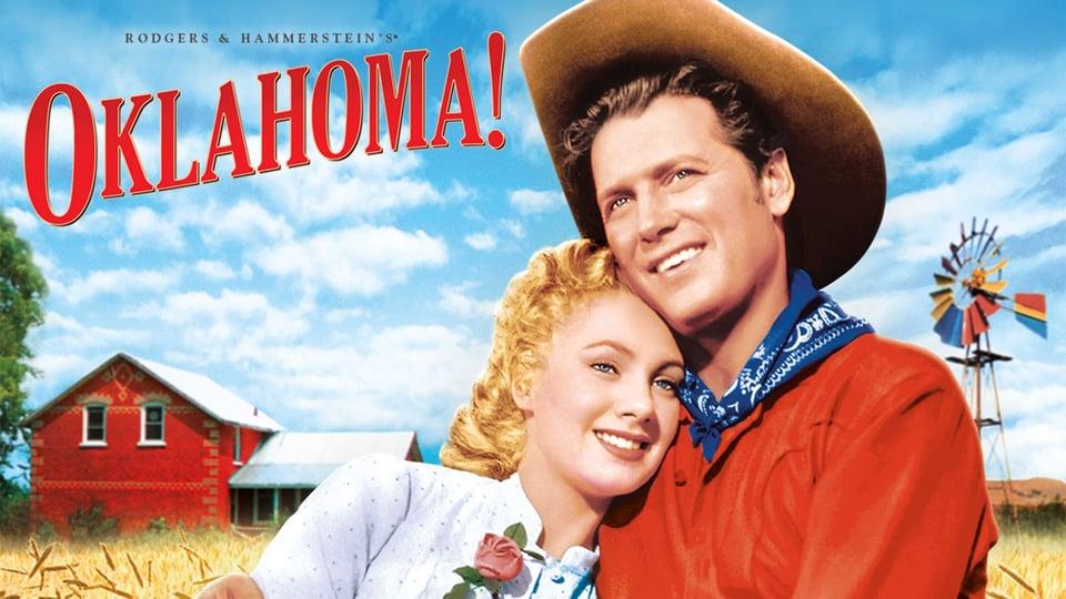 A couple in cowboy attire embrace in front of a farmhouse with "Oklahoma!" written above.