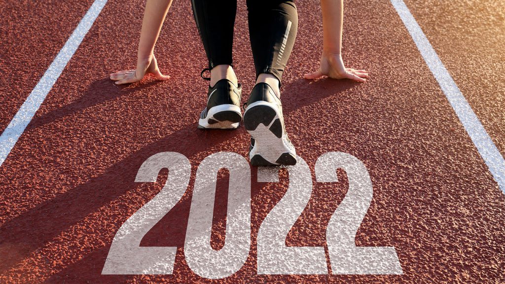 Person in running stance on track with "2022" written on the ground.