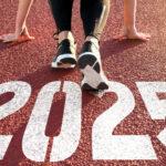 Person in running stance on track with "2025" painted on it, ready to start a race.