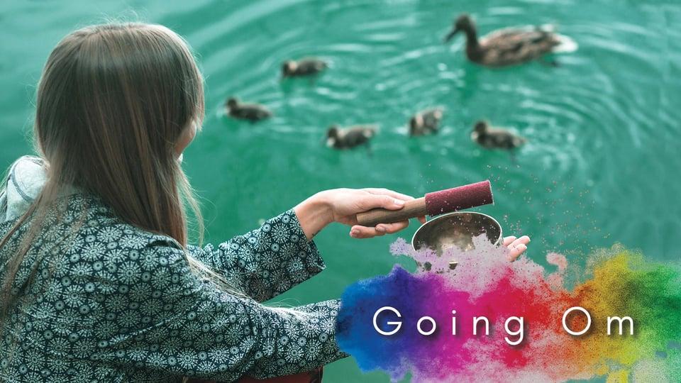 Person holding a singing bowl near a pond with ducks and colorful text overlay "Going Om".