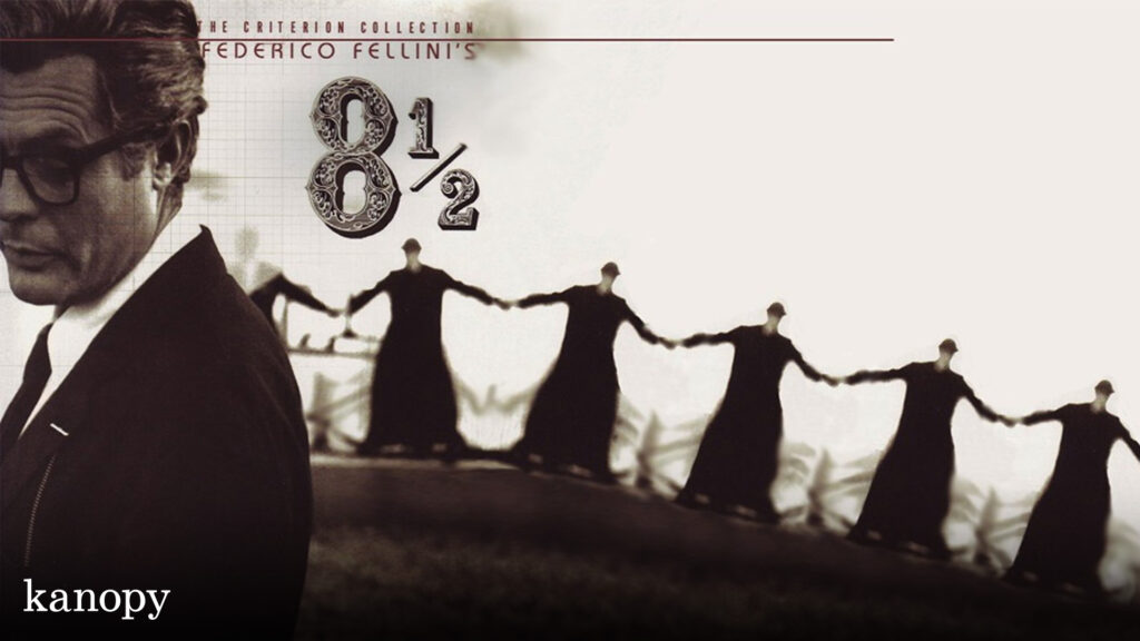 A man in glasses stands left as a line of people in black robes hold hands against a white background.