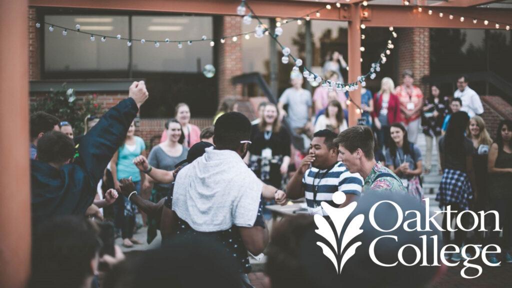 Students gathering outdoors under string lights with "Oakton College" logo in the foreground.