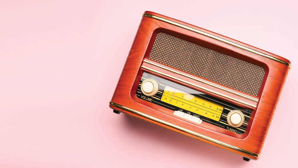 Vintage wooden radio on a pink background, angled slightly to the right.