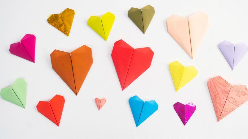 Colorful origami hearts of various sizes arranged on a white background.