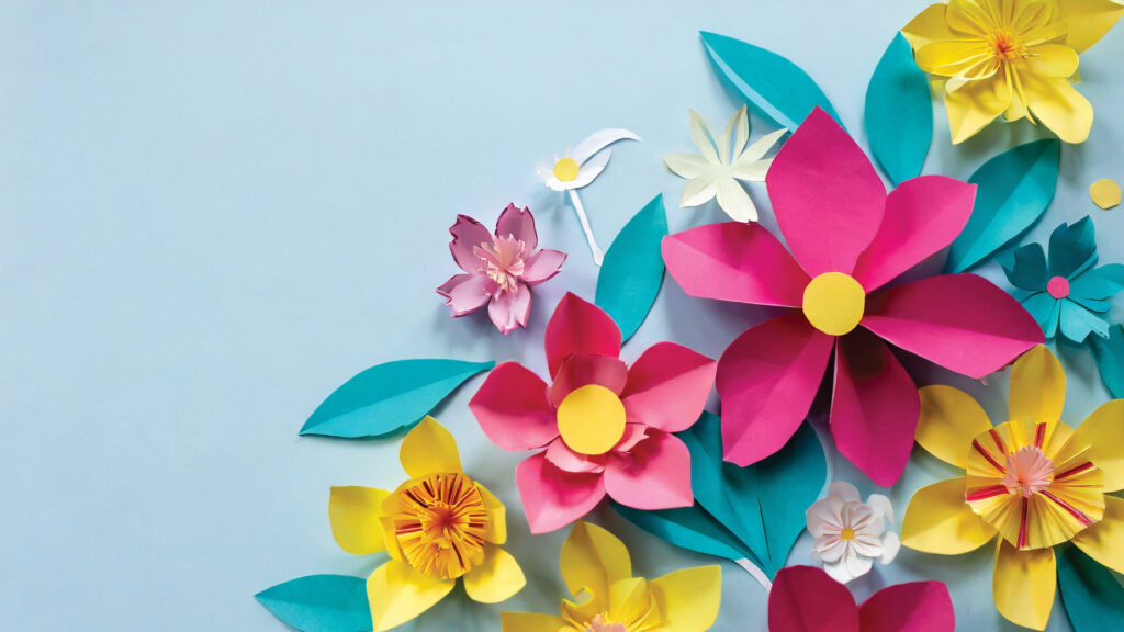 Colorful paper flowers and green leaves on a light blue background, arranged in a corner pattern.