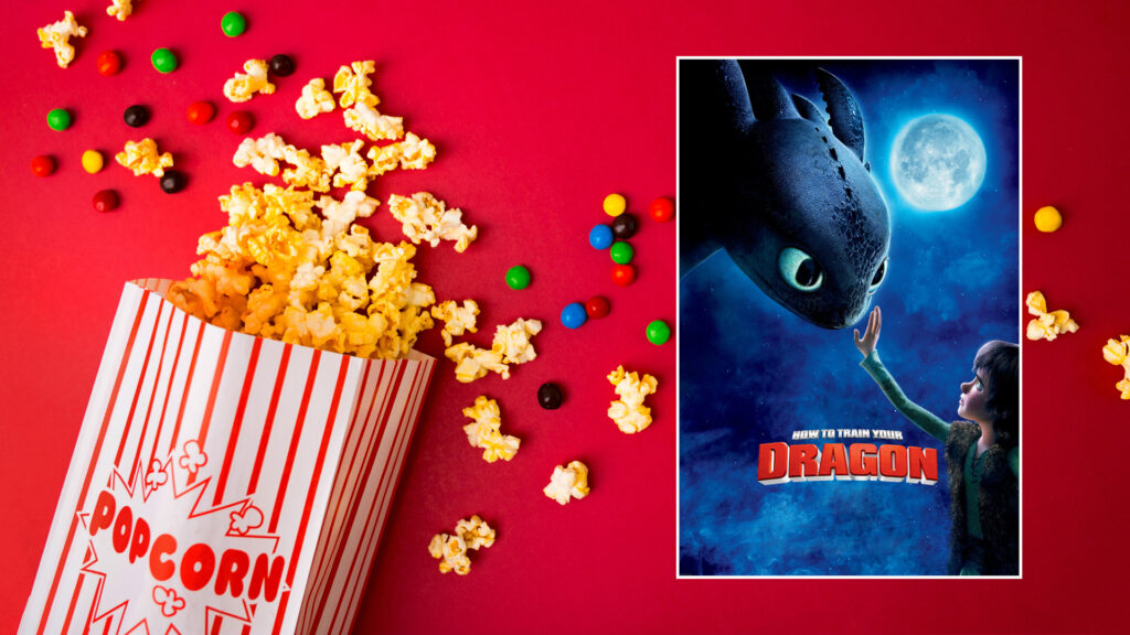 Popcorn and candy spill beside a "How to Train Your Dragon" movie poster on a red background.