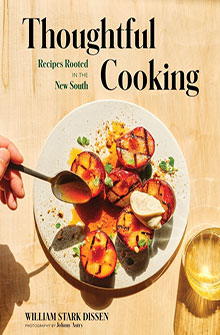 A hand plates grilled peaches with cream on a wooden table, beside a glass and the book title "Thoughtful Cooking".
