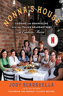 Nine women sit around a table with Italian food, smiling on the cover of "Nonna's House" cookbook.