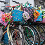 Colorful bicycles with woven baskets decorated with flowers lined up in a row.