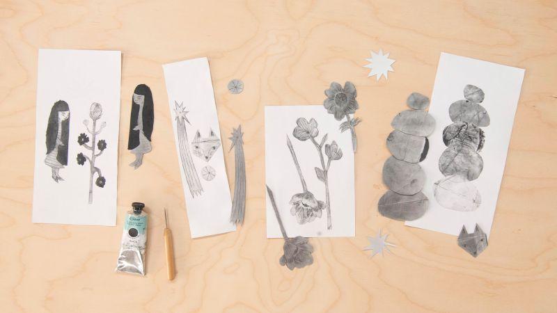 Pencil sketches of plants and stones on paper with a small paint tube on a wooden surface.