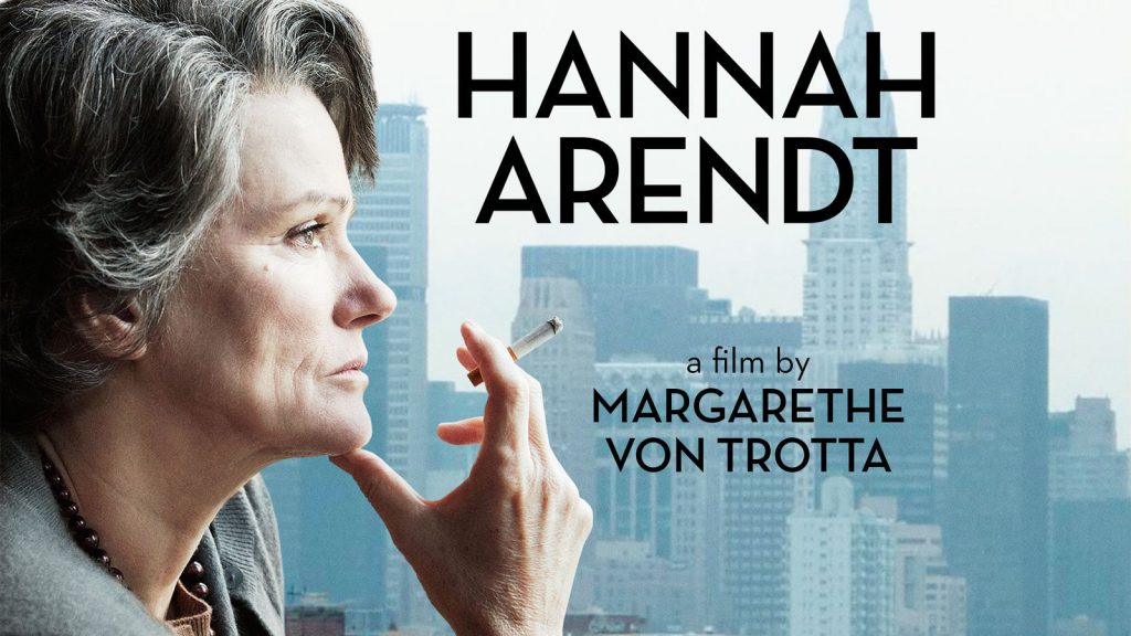 A woman holding a cigarette looks out at a city skyline. Text: "Hannah Arendt, a film by Margarethe von Trotta.