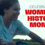 Smiling woman rides a bicycle outdoors. Text: Celebrating Women’s History Month. Kanopy logo in corner.