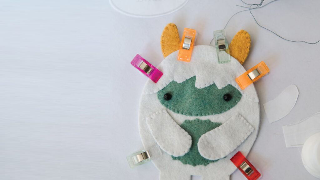 A felt monster craft with clips attached, ready to be sewn, on a white background.